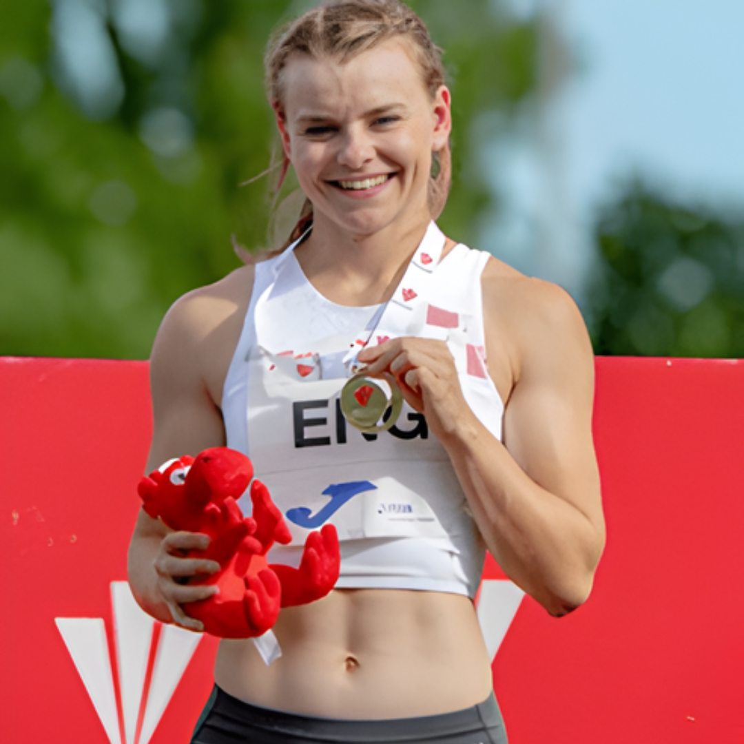 Ellie, a sprinter on podium smiling with medal at competition.