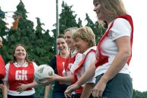 Group of women laughing with eachother holding a netball.