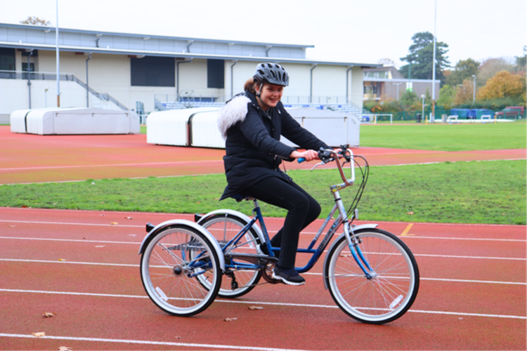 girl on inclusive bike cycling around athletics track