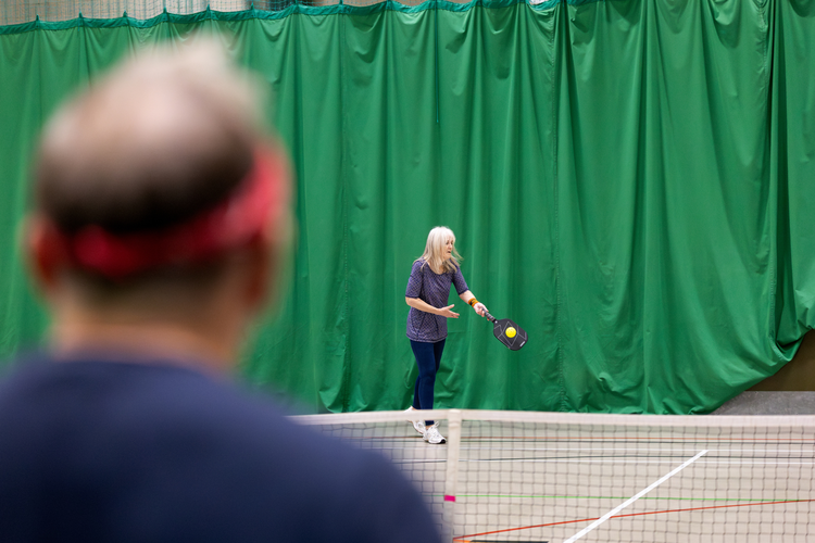 Older lady playing pickleball indoors.