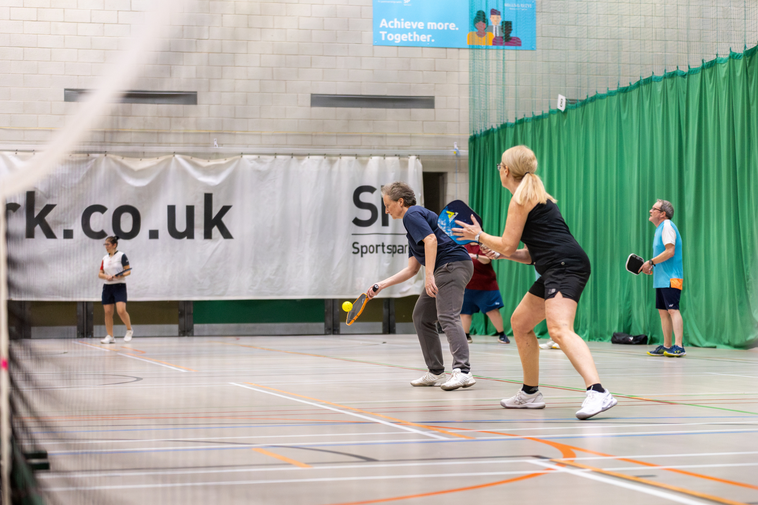 Ladies in their 50s playing pickleball doubles.