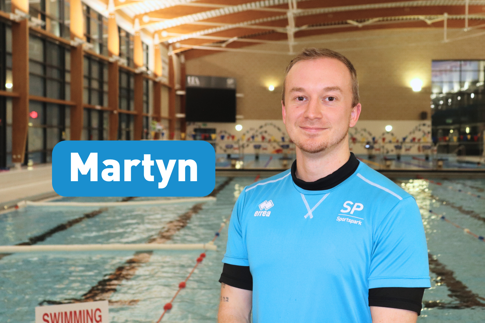 Headshot of Martyn smiling at camera in front of indoor 50m pool.