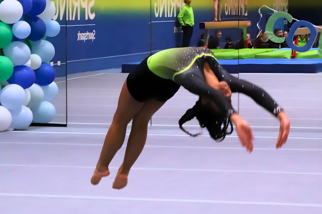 Girl in the air mid back handspring on gymnastics floor.