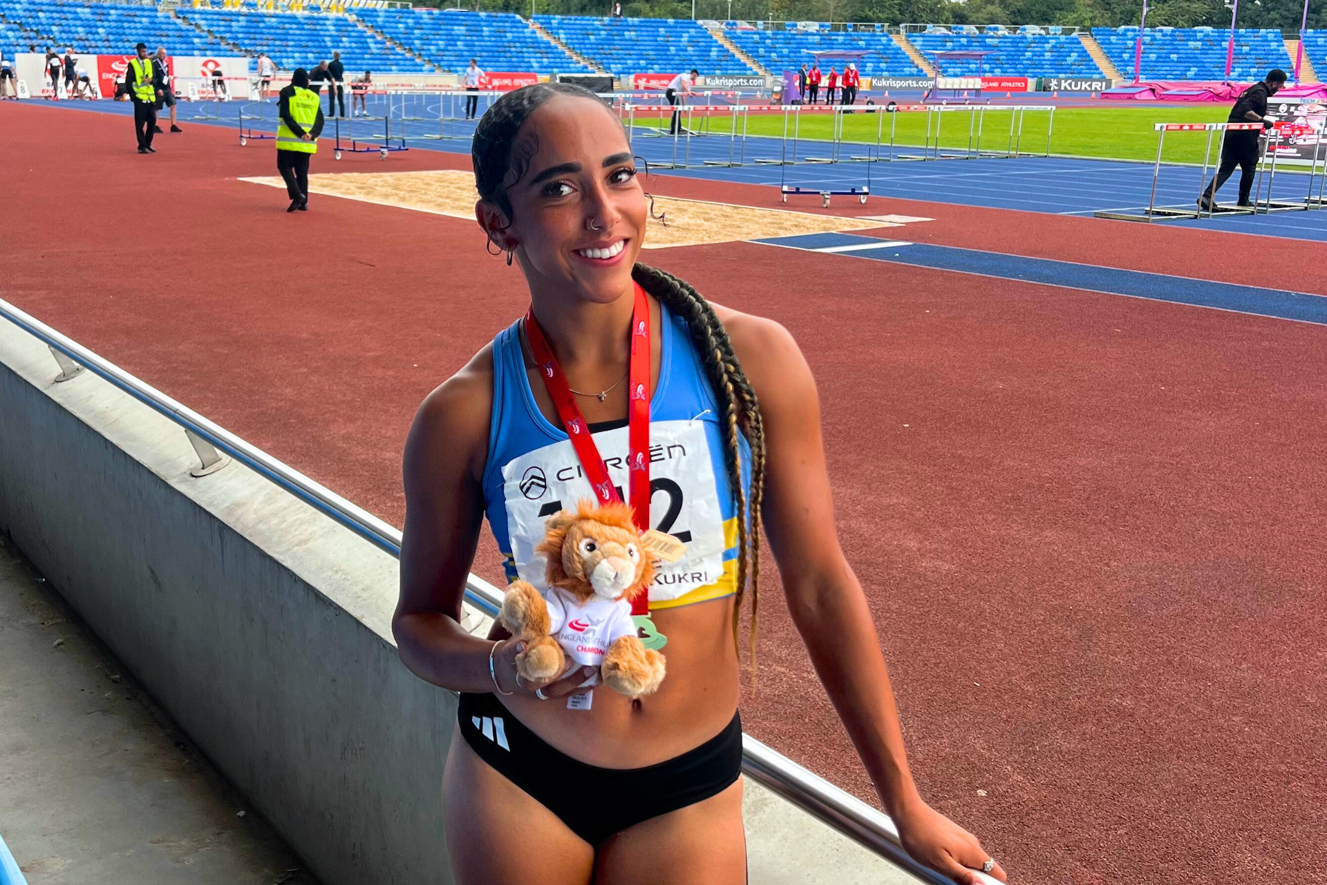 Serena Grace on athletics track with medal smiling at camera.