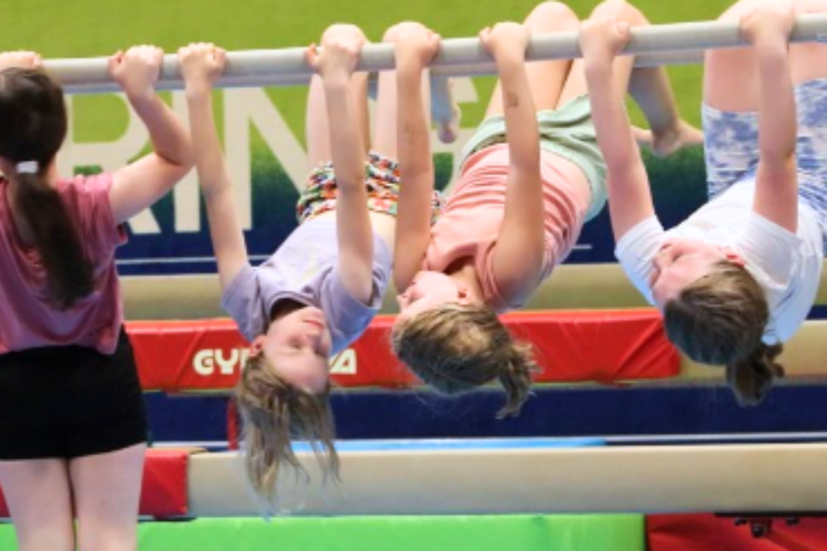 Girls hanging upside down from gymnastics barres.