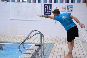 swimming teacher showing front crawl stroke on side of pool