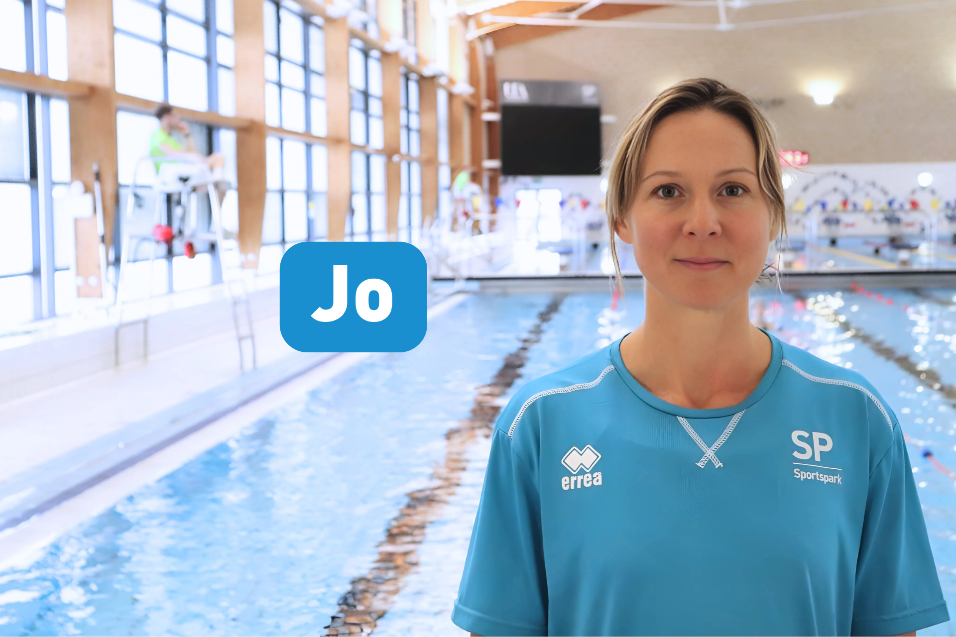 Headshot of Jo smiling at camera standing in front of 50 indoor pool.