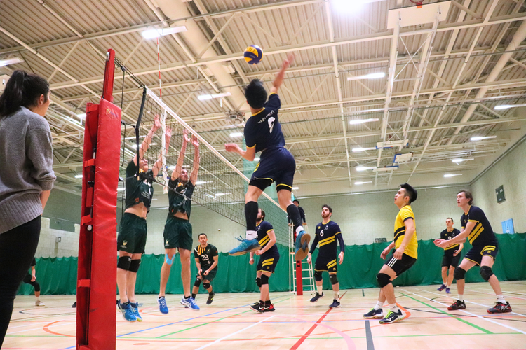 Boy spike volleyball over net.