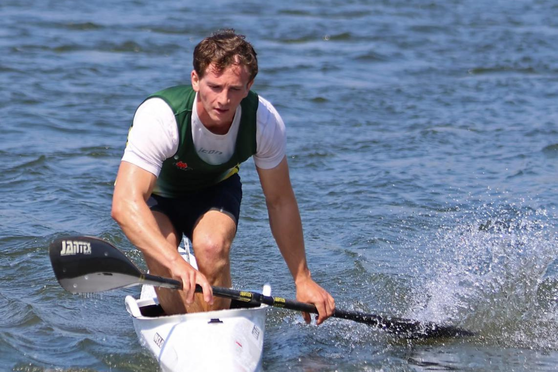 James How standing on kayak on lake.