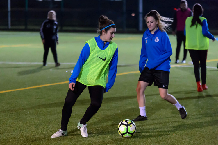 Two women playing football at night.