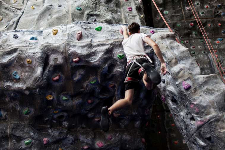 Boy hanging from climbing wall.