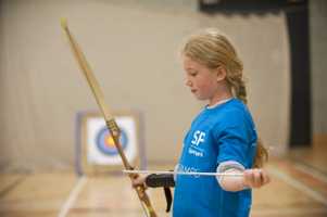 young girl setting up an archery bow in front of target