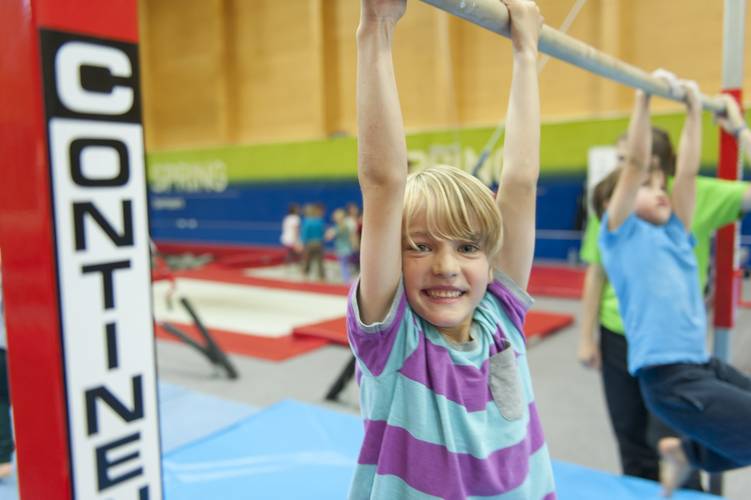 boy on gymnastics bars smiling at camera