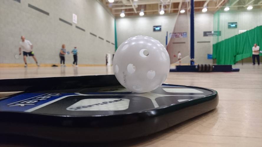 pickleball bat on floor with ball on top