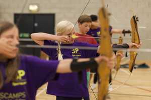 Group of children holding bows doing archery.