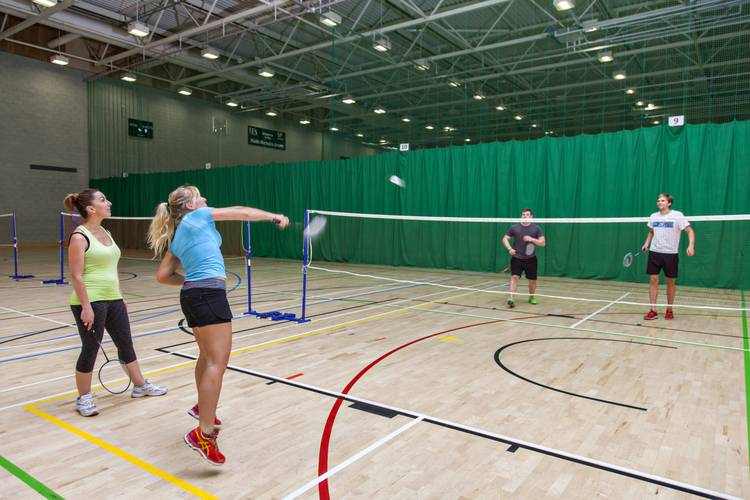 Two men and two women playing badminton in sports hall