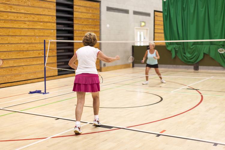 two older ladies playing badminton in sports hall