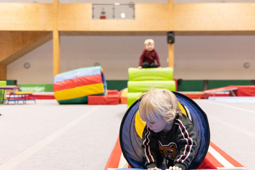 toddler crawling through tunnel in gymnastics centre