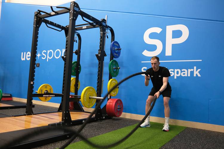 person using battle ropes in functional gym