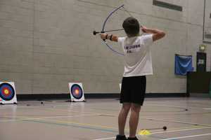 Child doing archery in sports hall.