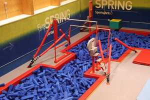 Uneven bars above foam pit in gymnastics centre.