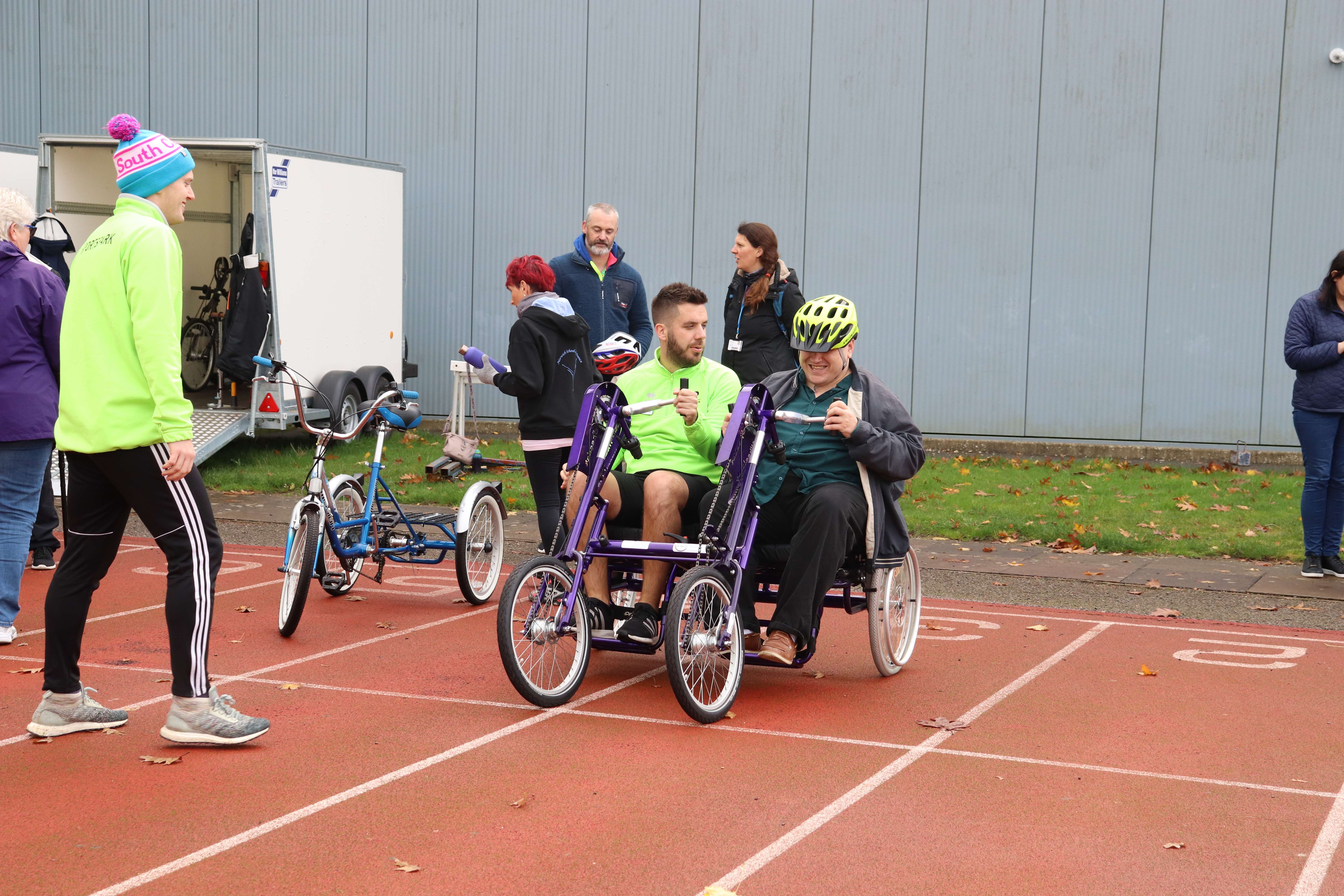 people using inclusive bikes on athletics track
