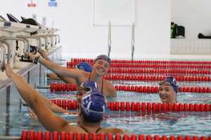group of young women in pool hanging on to the edge.