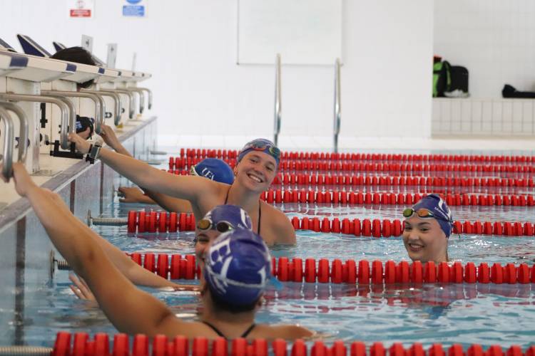 group of young women in pool hanging on to the edge.