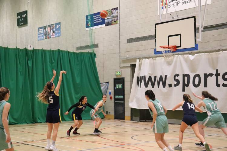 two female teams playing basketball. one girl shoots