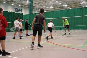 Three children lining up to play badminton with Sportspark coach.