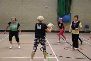 Women playing walking netball in indoor sport hall.
