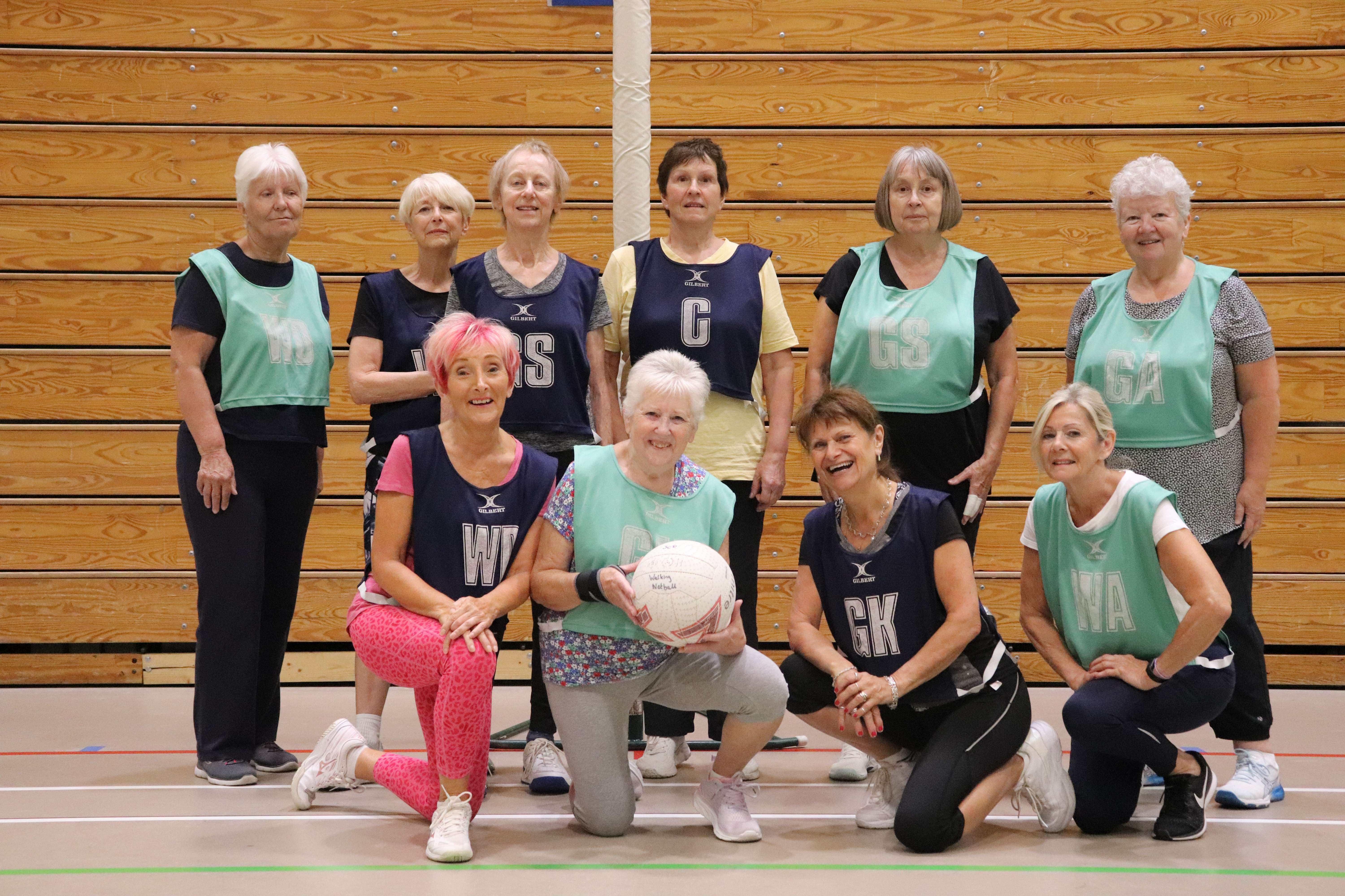 Group of older ladies posing with netball.