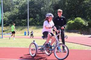 Girl on three wheel bike on athletics track.
