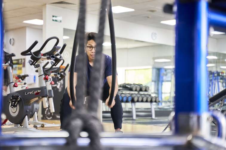 person using battle ropes in gym
