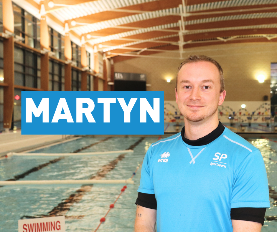 Male swim teacher in front of pool with name tag reading Martyn.